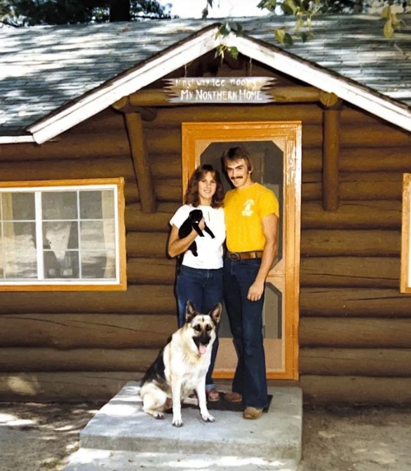 Man and woman with their cat and dog outside log cabin on Pelican Lake MN